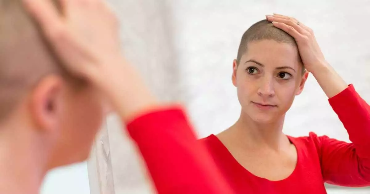 Woman looking concerned in the mirror rubbing her short hair with her hand. hair loss concept.